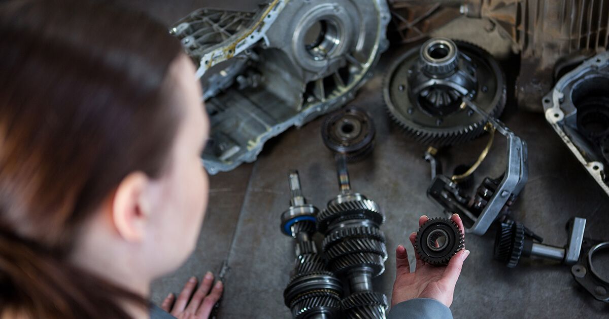 Woman looking down at automotive parts.